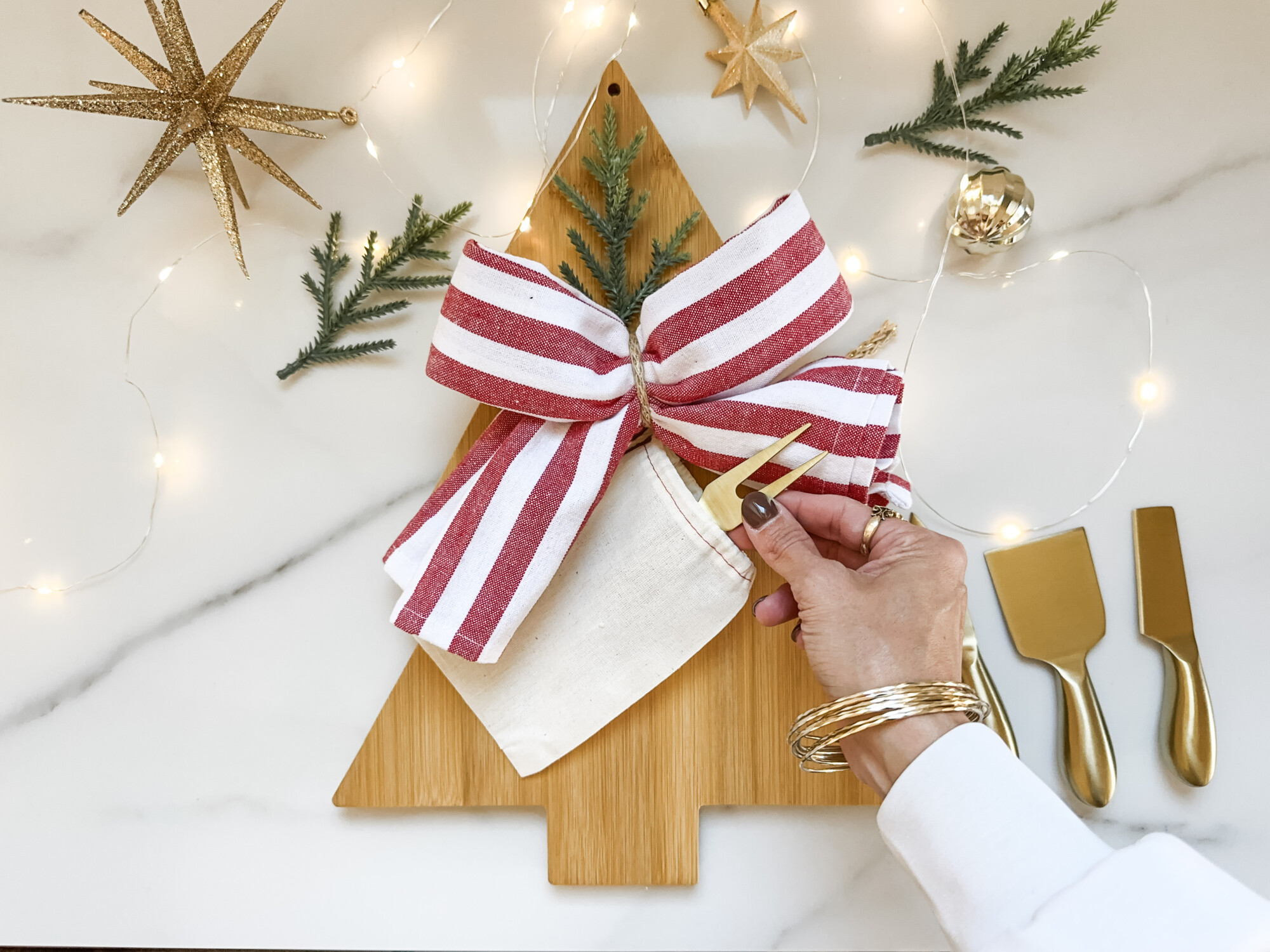 thoughtful and affordable diy host gifts under $35 | host gifts, diy gifts, gift ideas, handmade gift, gift ideas, cutting board, cheese utensils, gold knives, neutral bag, star ornament, striped bow, decorative bow, striped towel