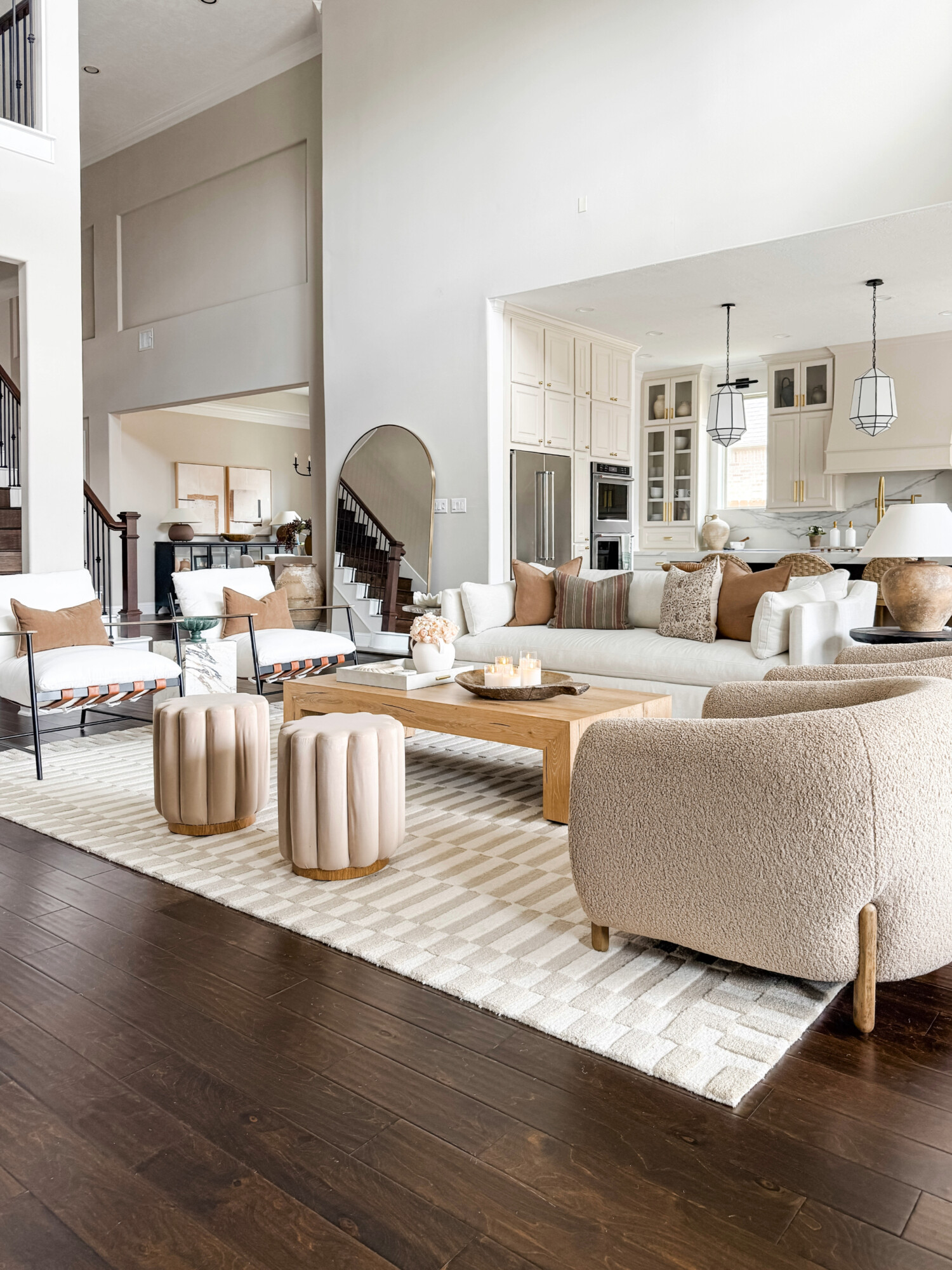 beige living room with kathy kuo accent chairs, kathy kuo sofa, waterfall coffee table, and walmart ottomans