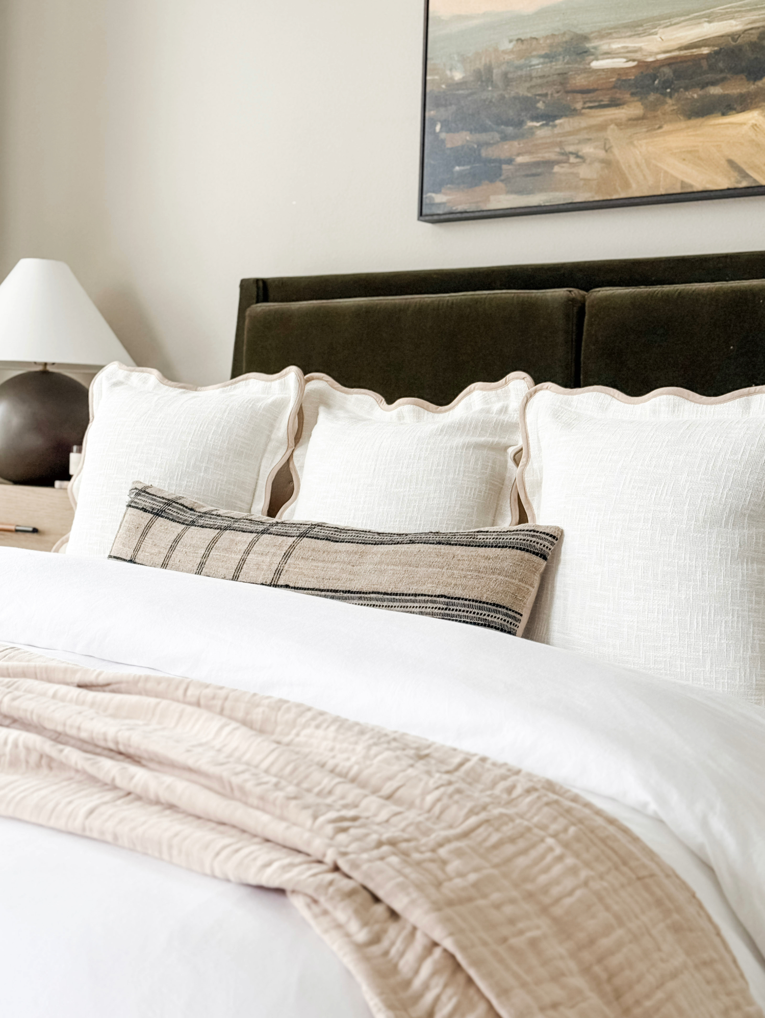 beige master bed with scalloped pillows and lumbar