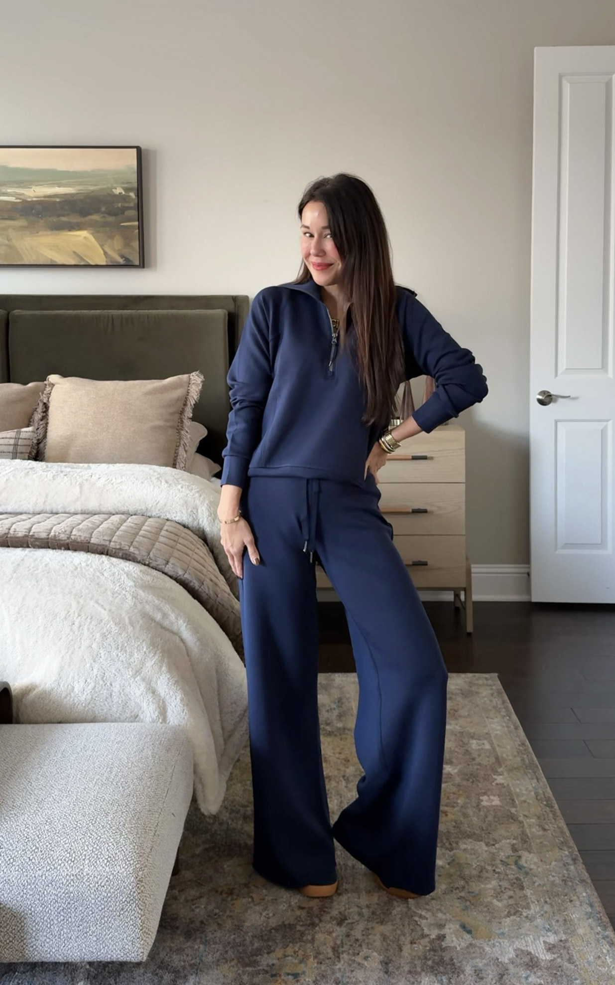 Woman wearing a navy lounge set styled in a neutral bedroom