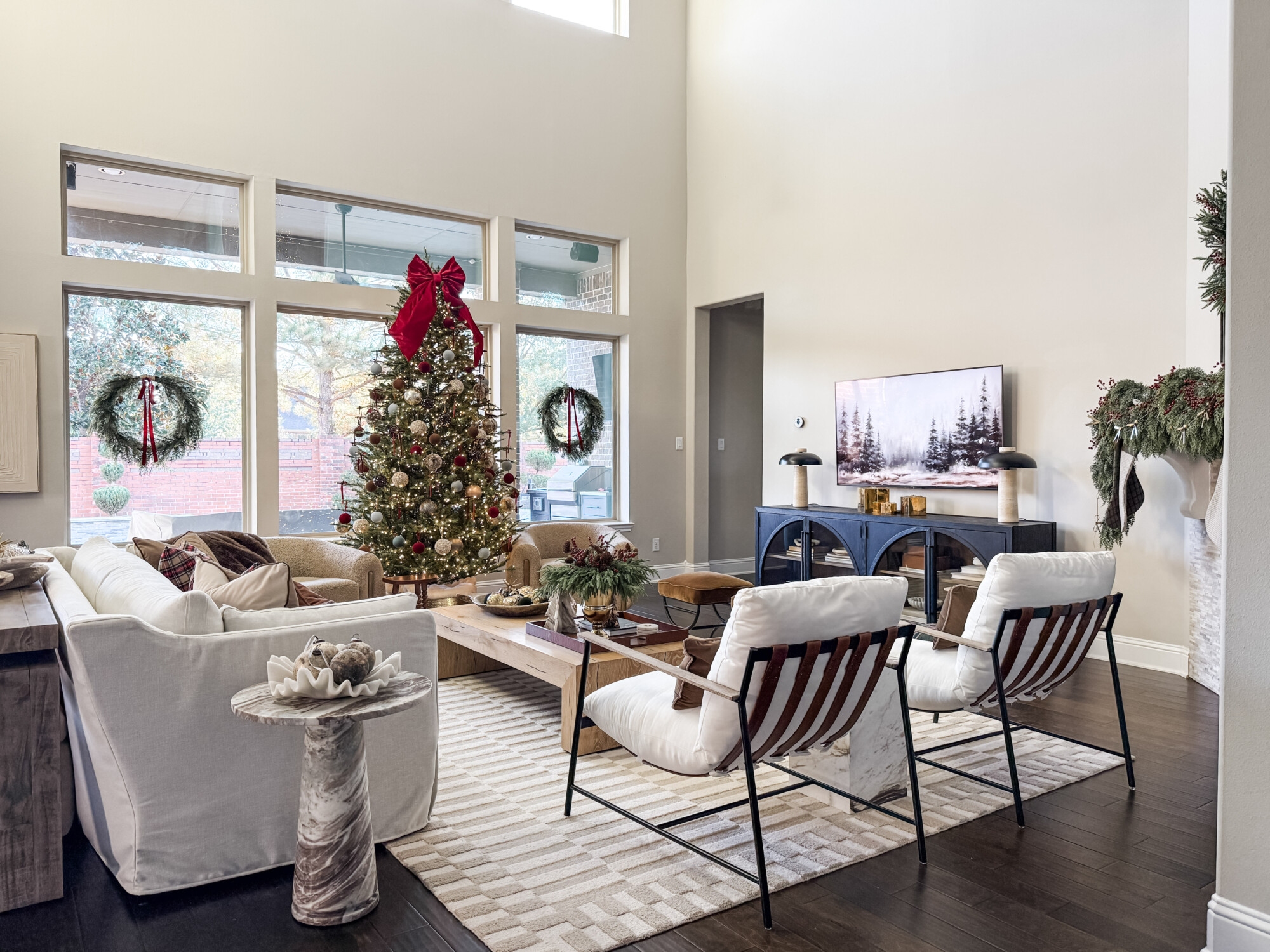 Holiday living room with a decorated Christmas tree, neutral seating, layered textures, and greenery accents, creating a warm and inviting seasonal look.