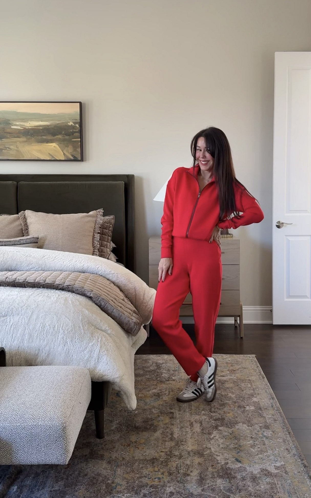 Woman wearing a red lounge set styled in a neutral bedroom with soft bedding