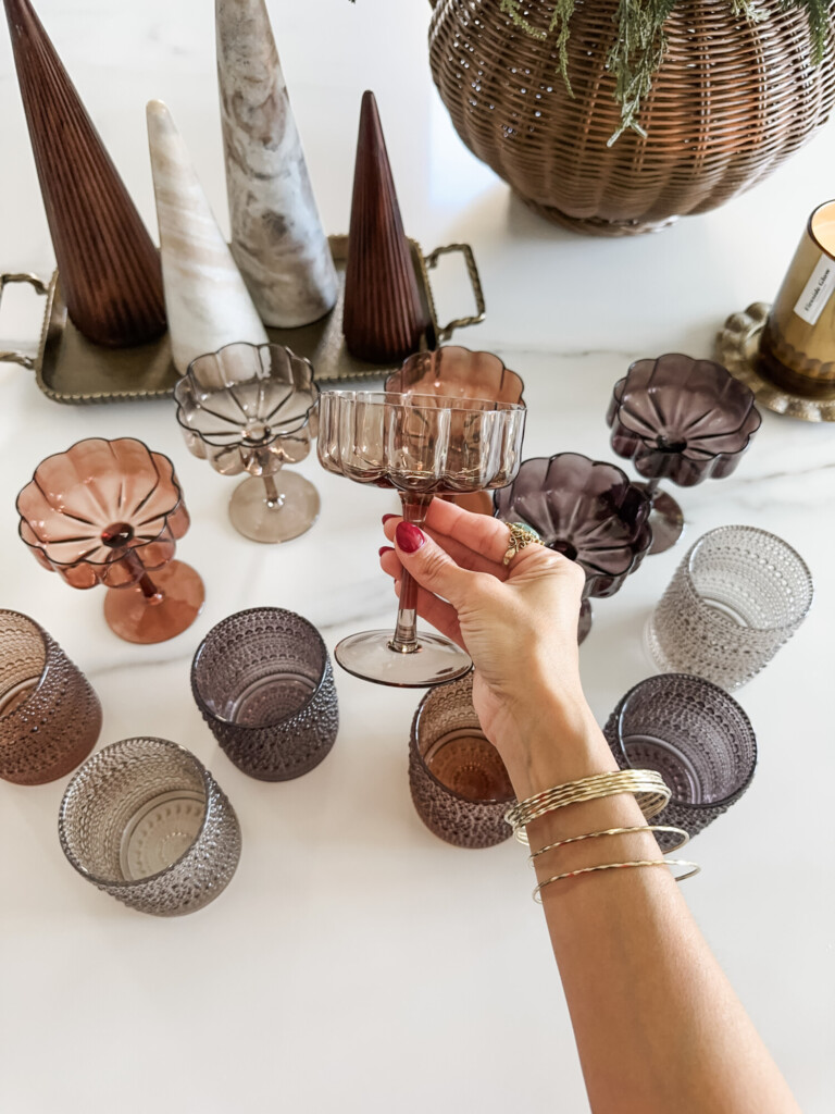 Textured glass coupe glasses and votive candles styled on a marble surface for holiday hosting