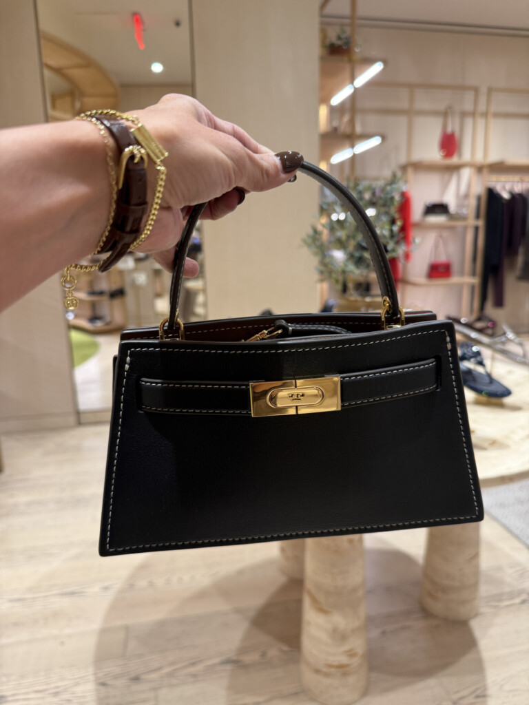 Black structured leather handbag with gold hardware styled in a boutique setting