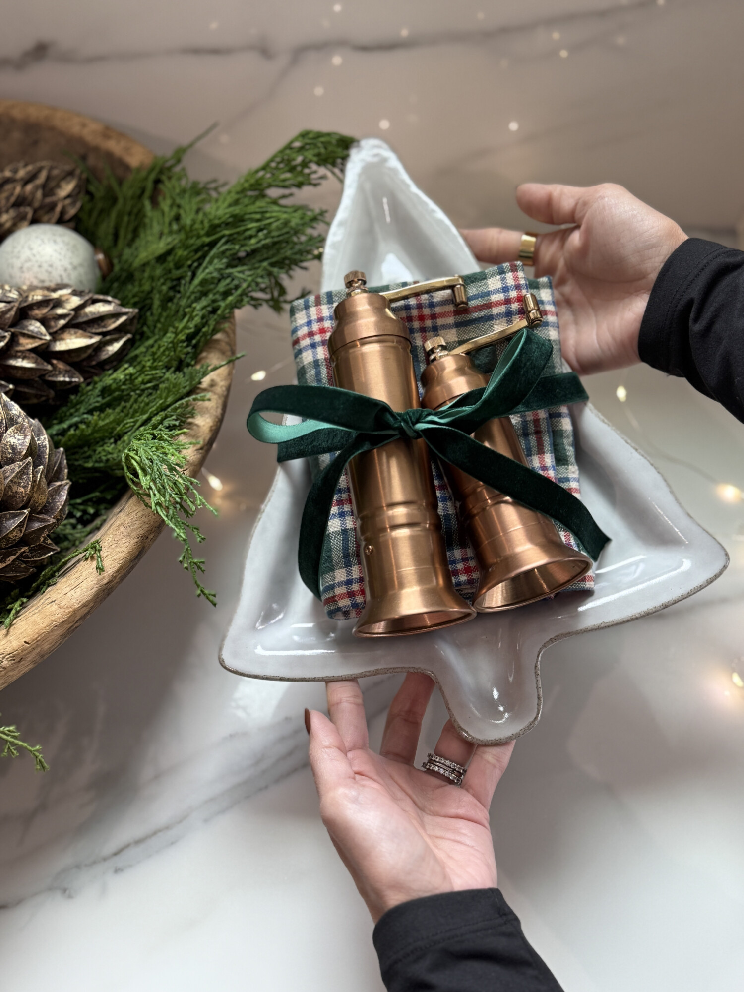 Copper salt and pepper grinders tied with a green ribbon on a ceramic holiday serving dish